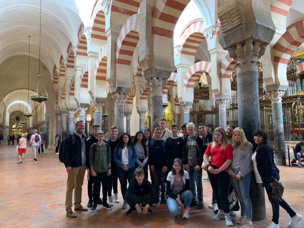 Die Gruppe steht mit ihren Begleitern zwischen den Bögen der Mezquita.